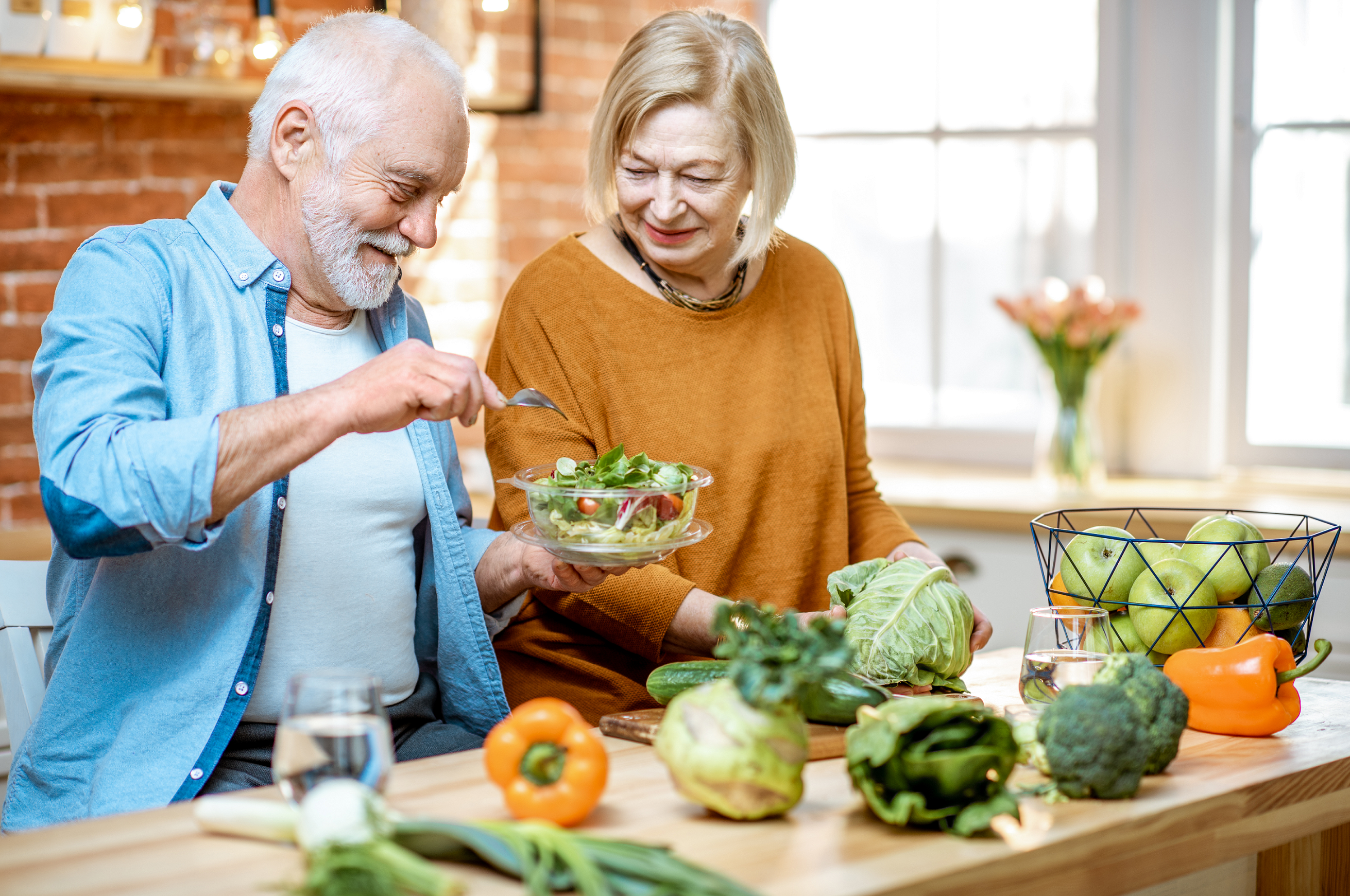 Starsza para przygotowująca sałatkę na obniżenie cholesterolu